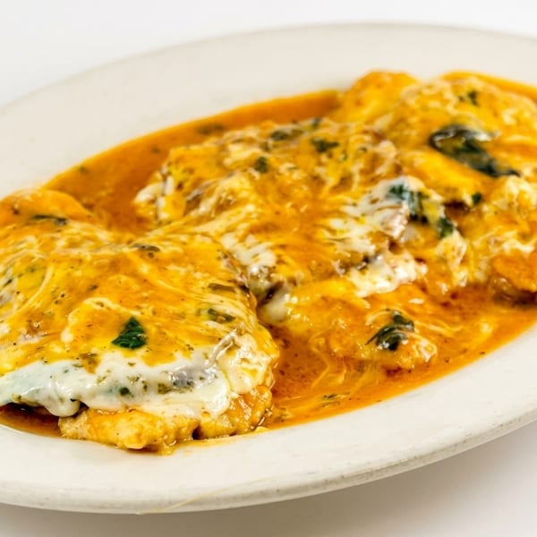 Chicken parmesan with melted cheese and red sauce on a white oval plate.