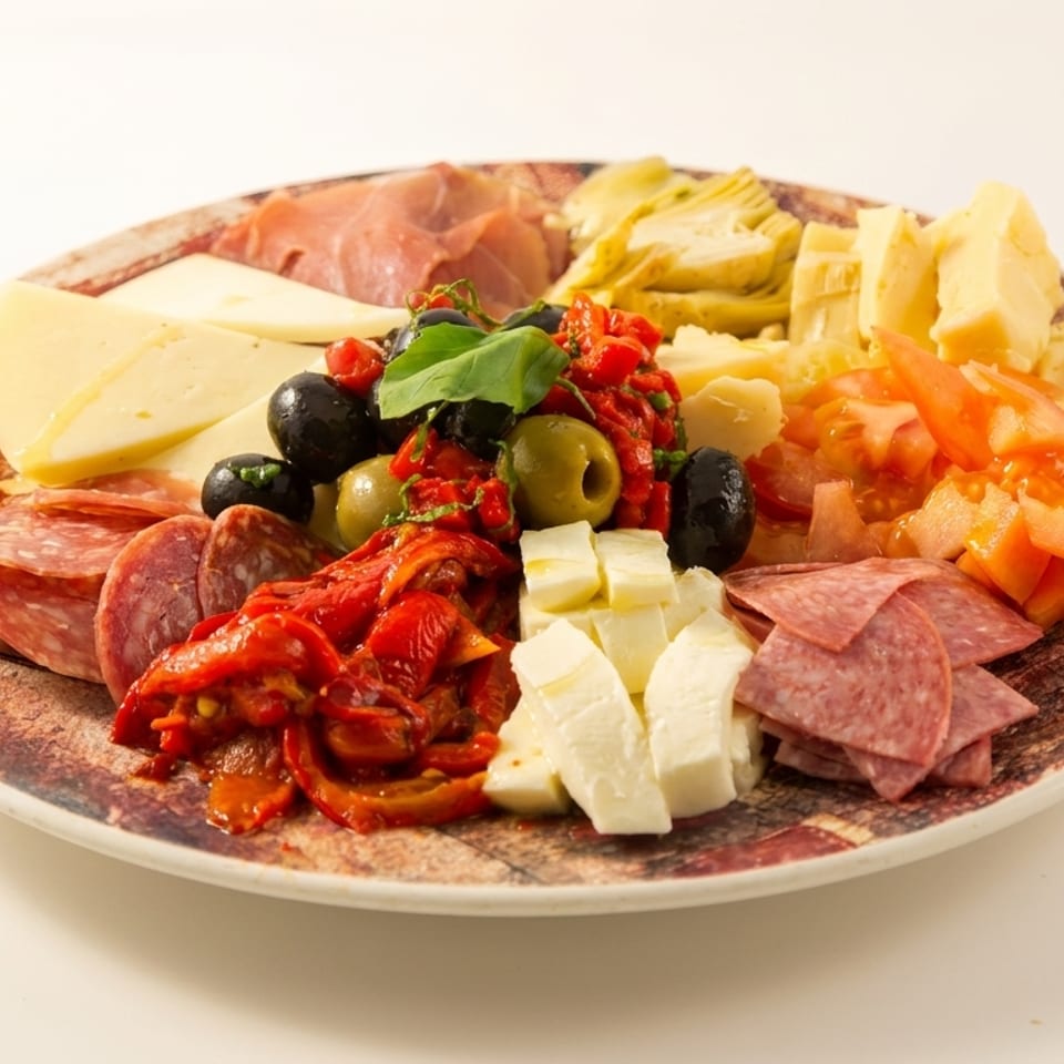 A colorful antipasto platter with various cheeses, meats, olives, sun-dried tomatoes, and artichoke hearts.